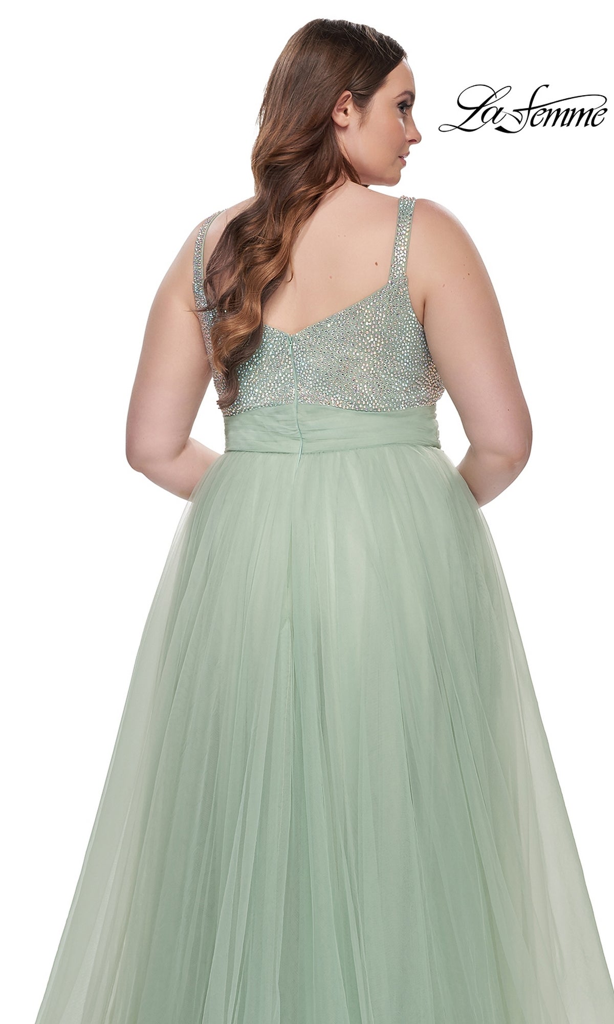 A woman faces away wearing the La Femme Long Prom Dress 31251—a sleeveless mint green plus-size gown with a beaded bodice and a flowing tulle skirt.